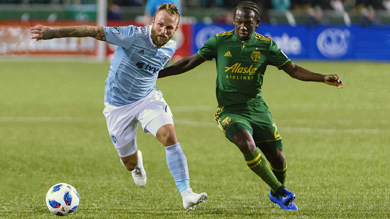 Sporting KC's Johnny F. Russell holds of Portland Timbers' Diego Charra in an MLS match at Providence Park in Portland.